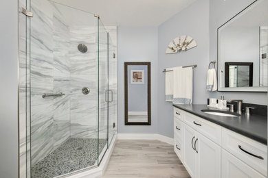 Large nautical ensuite bathroom in Tampa with shaker cabinets, white cabinets, a corner shower, a two-piece toilet, white tiles, porcelain tiles, blue walls, ceramic flooring, a submerged sink, engineered stone worktops, beige floors, a hinged door, black worktops, double sinks and a vaulted ceiling.