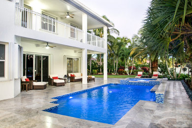 Mid-sized contemporary backyard pool in Miami with natural stone pavers.