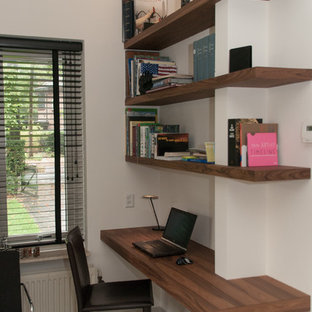 Exempel på ett modernt hemmabibliotek, med vita väggar, travertin golv och ett inbyggt skrivbord