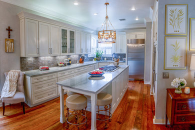 Example of a mid-sized transitional u-shaped medium tone wood floor and brown floor kitchen design in Other with an undermount sink, recessed-panel cabinets, white cabinets, quartzite countertops, gray backsplash, subway tile backsplash, stainless steel appliances, an island and gray countertops