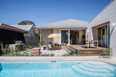 Diseño de piscina retro de tamaño medio en patio trasero con paisajismo de piscina y adoquines de piedra natural