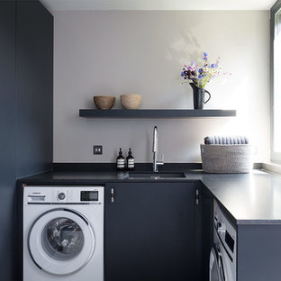 Foto de lavadero en U, contemporáneo, pequeño, con fregadero bajoencimera, encimera de mármol, suelo de madera clara, armarios con paneles lisos, puertas de armario negras, paredes grises, encimeras negras y lavadora y secadora integrada