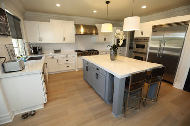 Eat-in kitchen - mid-sized modern u-shaped laminate floor and beige floor eat-in kitchen idea in Orange County with an undermount sink, shaker cabinets, white cabinets, quartz countertops, white backsplash, subway tile backsplash, stainless steel appliances, an island and white countertops