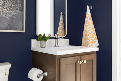 Inspiration for a small coastal blue tile and ceramic tile porcelain tile and blue floor powder room remodel in Minneapolis with shaker cabinets, medium tone wood cabinets, a two-piece toilet, blue walls, an integrated sink, solid surface countertops, white countertops and a freestanding vanity
