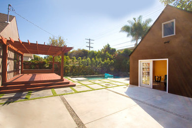 This is an example of a modern concrete paver back porch design in Los Angeles with a pergola.