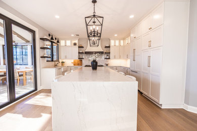 Example of a mid-sized transitional u-shaped medium tone wood floor and brown floor eat-in kitchen design in Baltimore with a farmhouse sink, shaker cabinets, white cabinets, quartz countertops, white backsplash, quartz backsplash, paneled appliances, an island and white countertops