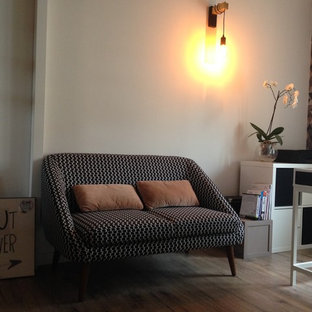 Photo of a mid-sized scandinavian study room in Marseille with multi-coloured walls, laminate floors, a wood stove, a built-in desk and black floor.