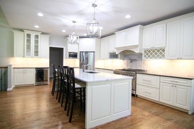 This is an example of a large traditional l-shaped open plan kitchen in Cincinnati with an undermount sink, raised-panel cabinets, white cabinets, stainless steel appliances, light hardwood floors and with island.