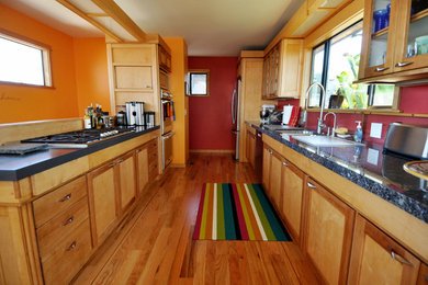 Mid-sized trendy galley medium tone wood floor and brown floor eat-in kitchen photo in San Luis Obispo with a double-bowl sink, shaker cabinets, medium tone wood cabinets, granite countertops, red backsplash, wood backsplash, stainless steel appliances and a peninsula