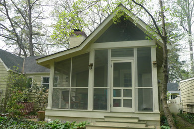 This is an example of a traditional screened-in back porch design in Other with a roof extension.
