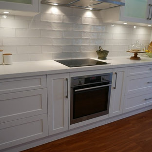 Mid-sized beach style kitchen pantry inspiration - Example of a mid-sized coastal galley laminate floor kitchen pantry design in Brisbane with an undermount sink, shaker cabinets, white cabinets, quartz countertops, white backsplash, subway tile backsplash, stainless steel appliances and an island