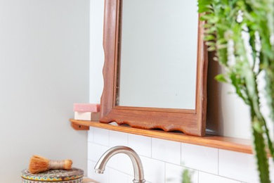 Inspiration for a small cottage white tile porcelain tile and gray floor corner shower remodel in Austin with wood countertops and brown countertops