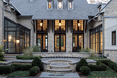 This is an example of a traditional three-storey grey exterior in Milwaukee with stone veneer and a hip roof.