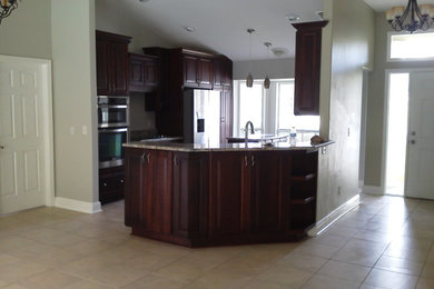 Photo of a traditional eat-in kitchen in Orlando with raised-panel cabinets, dark wood cabinets, granite benchtops, stainless steel appliances and with island.