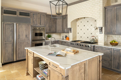 Eat-in kitchen - huge country l-shaped porcelain tile and beige floor eat-in kitchen idea in Philadelphia with a farmhouse sink, recessed-panel cabinets, brown cabinets, quartzite countertops, beige backsplash, ceramic backsplash, stainless steel appliances, an island and beige countertops