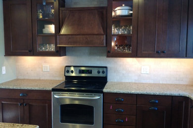 Mid-sized elegant u-shaped ceramic tile and beige floor kitchen photo in Philadelphia with an undermount sink, recessed-panel cabinets, dark wood cabinets, granite countertops, stone tile backsplash, stainless steel appliances, an island, brown countertops and gray backsplash