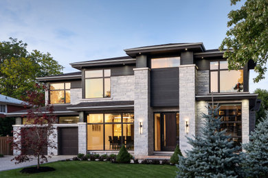 Contemporary two-storey grey house exterior in Toronto with stone veneer, a hip roof and a shingle roof.