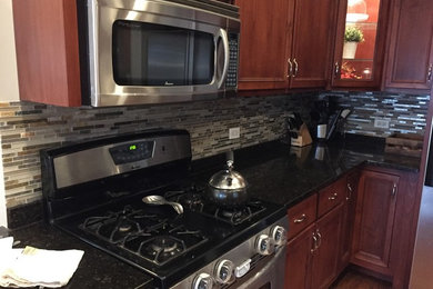 Minimalist kitchen photo in Chicago with recessed-panel cabinets, brown cabinets, gray backsplash, glass tile backsplash and stainless steel appliances