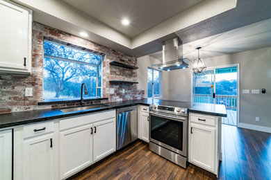 Example of a mid-sized transitional u-shaped dark wood floor and brown floor enclosed kitchen design in Other with recessed-panel cabinets, white cabinets, granite countertops, red backsplash, brick backsplash, stainless steel appliances and a peninsula