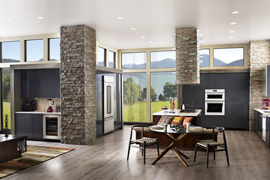 Example of a minimalist u-shaped eat-in kitchen design in Cleveland with flat-panel cabinets, gray cabinets, beige backsplash, stainless steel appliances and an island