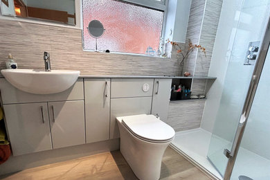 Photo of a medium sized modern family bathroom in Other with flat-panel cabinets, grey cabinets, a walk-in shower, a one-piece toilet, grey tiles, porcelain tiles, white walls, laminate floors, a built-in sink, laminate worktops, brown floors, an open shower, grey worktops, a single sink and a built in vanity unit.