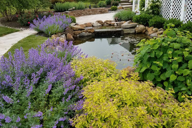 Ejemplo de jardín de estilo de casa de campo grande en patio trasero con estanque y exposición total al sol