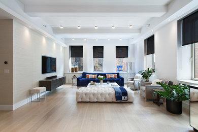 Photo of a large contemporary formal open concept living room in New York with beige walls, light hardwood floors, a concealed tv, no fireplace and beige floor.