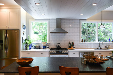 Photo of a mid-sized country u-shaped open plan kitchen in Raleigh with an undermount sink, recessed-panel cabinets, white cabinets, marble benchtops, white splashback, subway tile splashback, stainless steel appliances, medium hardwood floors, with island, brown floor and white benchtop.