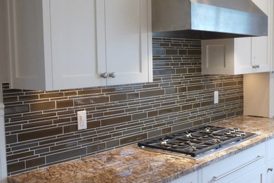 Large elegant l-shaped light wood floor eat-in kitchen photo in Portland with an undermount sink, shaker cabinets, white cabinets, granite countertops, green backsplash, mosaic tile backsplash, stainless steel appliances and an island