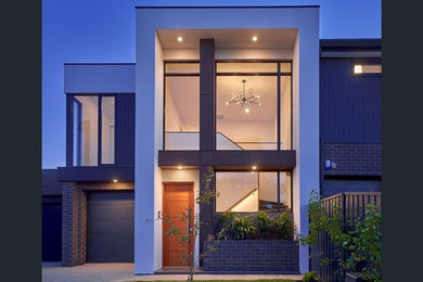 Photo of a large and black modern two floor brick terraced house in Adelaide with a flat roof and a metal roof.