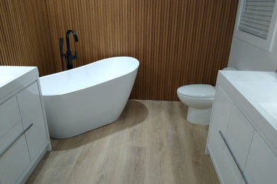 Example of a mid-sized minimalist master vinyl floor, beige floor and single-sink bathroom design in Toronto with flat-panel cabinets, white cabinets, a one-piece toilet, white walls, an integrated sink, onyx countertops, a hinged shower door, white countertops and a freestanding vanity
