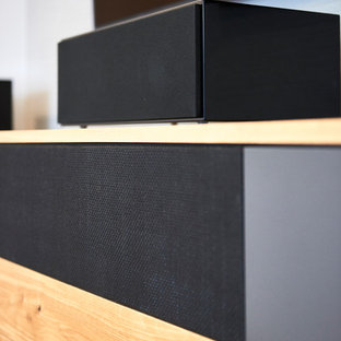 Example of a mid-sized trendy open concept medium tone wood floor and brown floor home theater design in Nuremberg with gray walls and a media wall