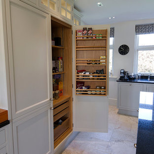 Large traditional kitchen pantry photos - Kitchen pantry - large traditional u-shaped limestone floor kitchen pantry idea in Buckinghamshire with a double-bowl sink, recessed-panel cabinets, gray cabinets, granite countertops, white backsplash, ceramic backsplash, black appliances and an island