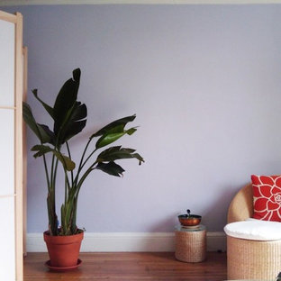 Immagine di un piccolo soggiorno minimalista chiuso con pareti viola, pavimento in legno massello medio, nessun camino, nessuna TV e pavimento marrone