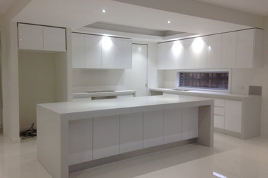 Inspiration for a large modern eat-in kitchen in Melbourne with an undermount sink, white cabinets, quartzite benchtops, white splashback, glass tile splashback, stainless steel appliances, porcelain floors and with island.