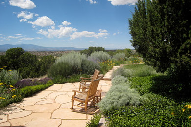 This is an example of a mid-sized mediterranean backyard full sun xeriscape for summer in Albuquerque with natural stone pavers.