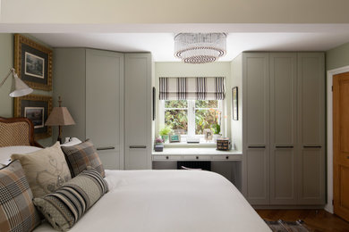 Eklektisches Hauptschlafzimmer mit grüner Wandfarbe und braunem Holzboden in Surrey
