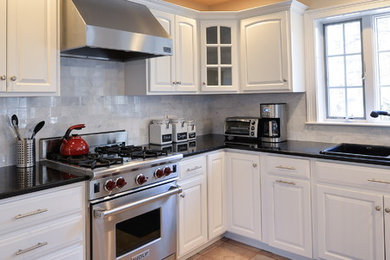 Example of a mid-sized transitional l-shaped kitchen design in Boston with raised-panel cabinets, white cabinets, granite countertops, marble backsplash, stainless steel appliances and black countertops