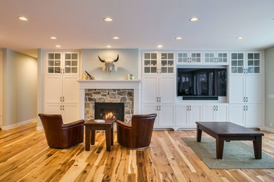 Mid-sized arts and crafts open concept medium tone wood floor living room photo in Other with green walls, a wood stove, a stone fireplace and a media wall