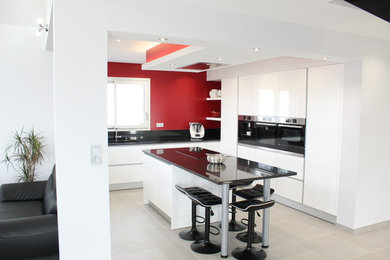 Idée de décoration pour une grande cuisine ouverte encastrable minimaliste en L avec un évier encastré, un placard à porte affleurante, des portes de placard blanches, un plan de travail en stratifié, une crédence noire, un sol en carrelage de céramique, îlot, un sol gris et plan de travail noir.