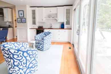 Photo of a large beach style eat-in kitchen in Boston with a drop-in sink, raised-panel cabinets, white cabinets, granite benchtops, white splashback, mosaic tile splashback, medium hardwood floors and with island.