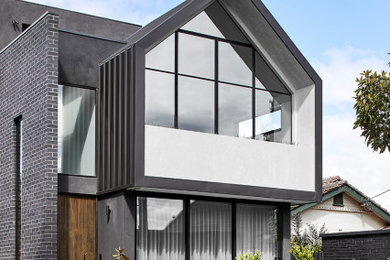 Modelo de fachada de casa pareada multicolor y negra moderna de tamaño medio de tres plantas con revestimiento de ladrillo, tejado plano y tejado de metal