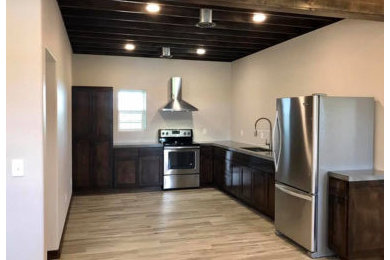 Example of a minimalist l-shaped gray floor enclosed kitchen design in Austin with shaker cabinets, dark wood cabinets, stainless steel appliances and no island