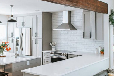 Mid-sized arts and crafts u-shaped medium tone wood floor, brown floor and exposed beam eat-in kitchen photo in Denver with a farmhouse sink, shaker cabinets, gray cabinets, quartz countertops, white backsplash, subway tile backsplash, stainless steel appliances, an island and white countertops