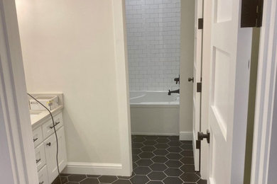 Example of a small minimalist white tile black floor, single-sink and brick wall tub/shower combo design in Phoenix with white cabinets, white countertops, a niche and a built-in vanity