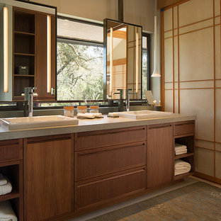 Cette photo montre une salle de bain asiatique avec un lavabo posé, un placard à porte plane et des portes de placard en bois brun.