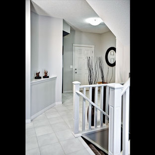 This is an example of a mid-sized eclectic foyer in Calgary with grey walls, ceramic floors, a pivot front door and a white front door.