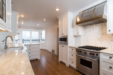 Inspiration for a mid-sized timeless galley medium tone wood floor eat-in kitchen remodel in Seattle with an undermount sink, shaker cabinets, white cabinets, marble countertops, white backsplash, porcelain backsplash, stainless steel appliances and a peninsula
