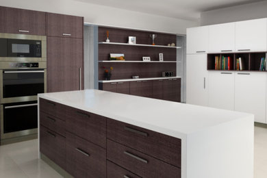 Photo of a mid-sized modern single-wall separate kitchen in Miami with flat-panel cabinets, dark wood cabinets, solid surface benchtops, stainless steel appliances, concrete floors, with island, grey floor and white benchtop.