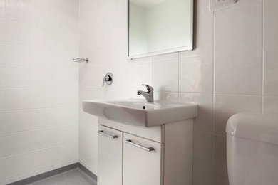 Photo of a mid-sized traditional 3/4 bathroom in Adelaide with a corner shower, a one-piece toilet, white tile, white walls and vinyl floors.